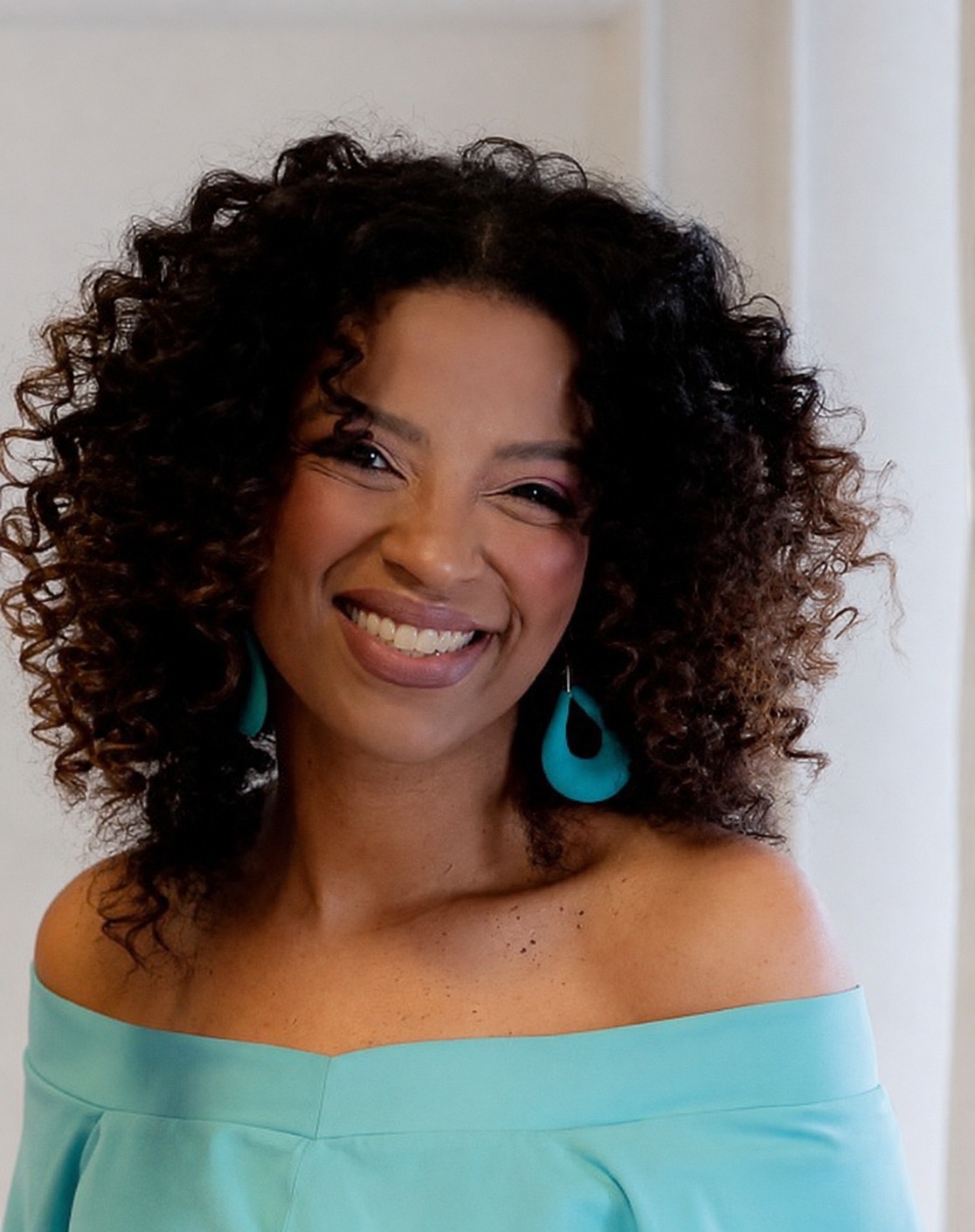 Aline Camargo smiling in a turquoise top